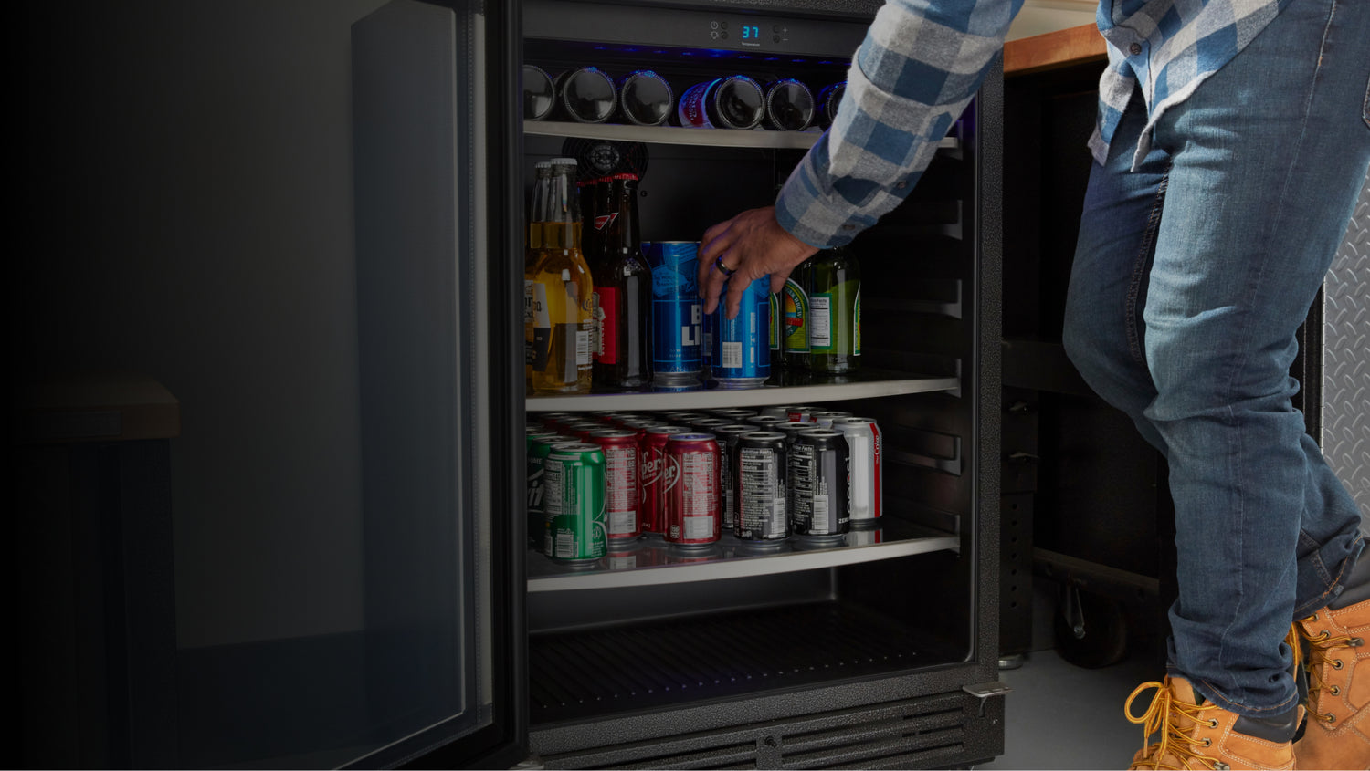 A person grabbing a beverage out of the Gladiator® beverage cooler