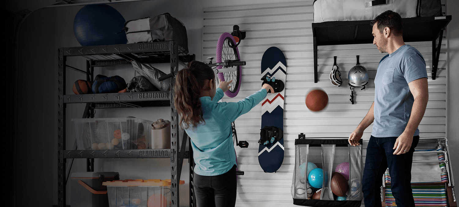 A dad and daughter organizing sports equipment in a garage